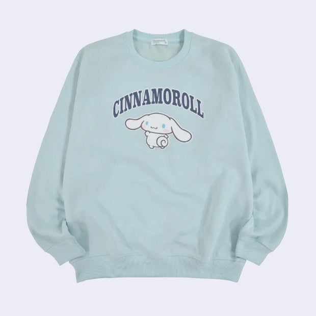 Baby blue pull over sweater featuring a graphic of Cinnamoroll, looking back over her shoulder and waving. Above, written in outlined capitalized letters says "Cinnamoroll".