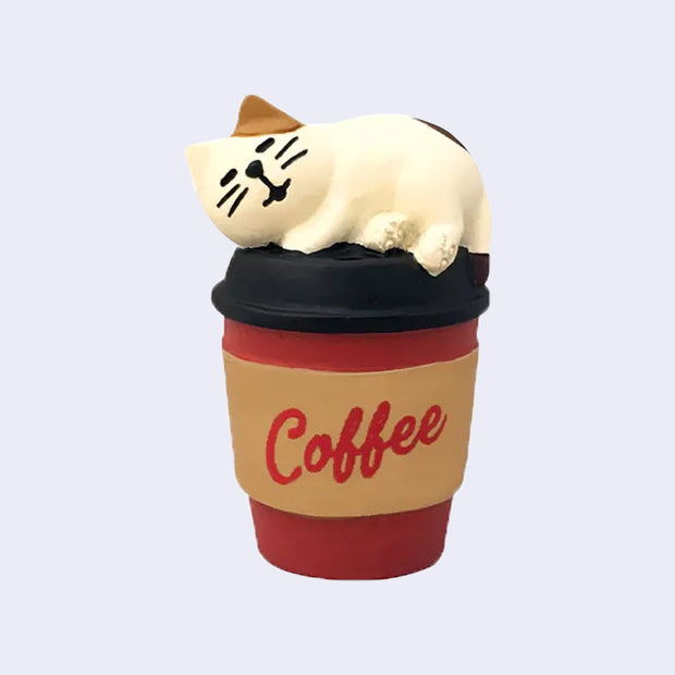 Small figure of calico cat sleeping on top of a cup of to-go coffee.
