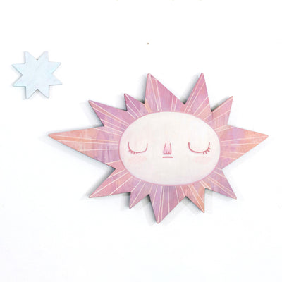 Sun-shaped wooden art piece with a face on a white background