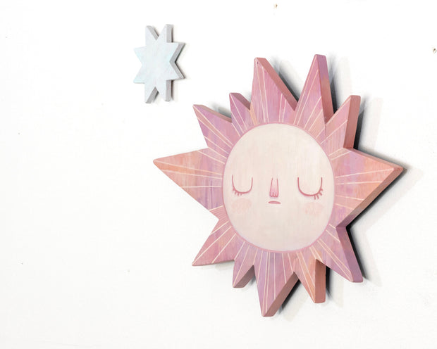 Sun-shaped wooden art piece with a face on a white background