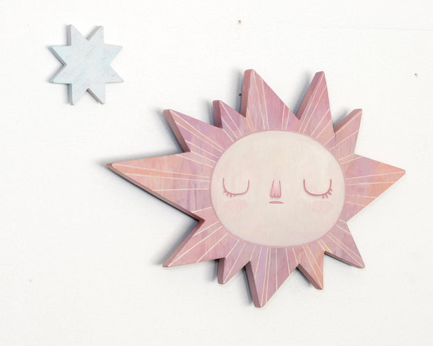 Sun-shaped wooden art piece with a face on a white background