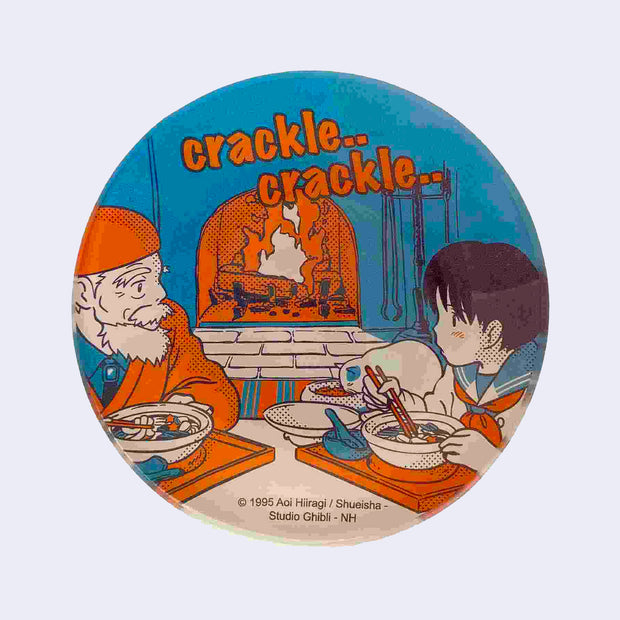 Blue and orange glass plate with an old man and a young girl from Whisper of the Heart. They sit in front of a crackling fireplace and eat soup. A cat eats as well. "crackle.. crackle.." is written along the top.