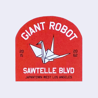 Red die cut arc shaped sticker, featuring an image of an origami crane and text that reads "Giant Robot" and "Sawtelle Blvd Japantown West Los Angeles"