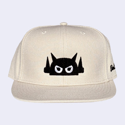 Beige cap with a black and white graphic design on a light gray background