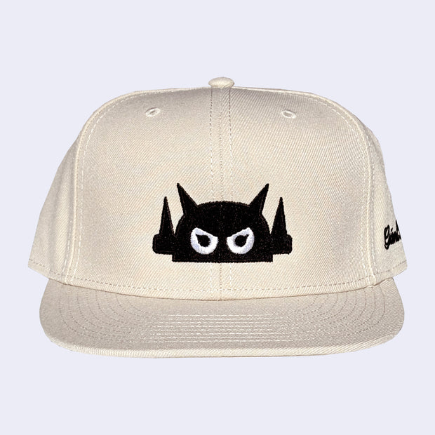 Beige cap with a black and white graphic design on a light gray background