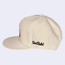 Beige cap with black embroidered text on a light gray background