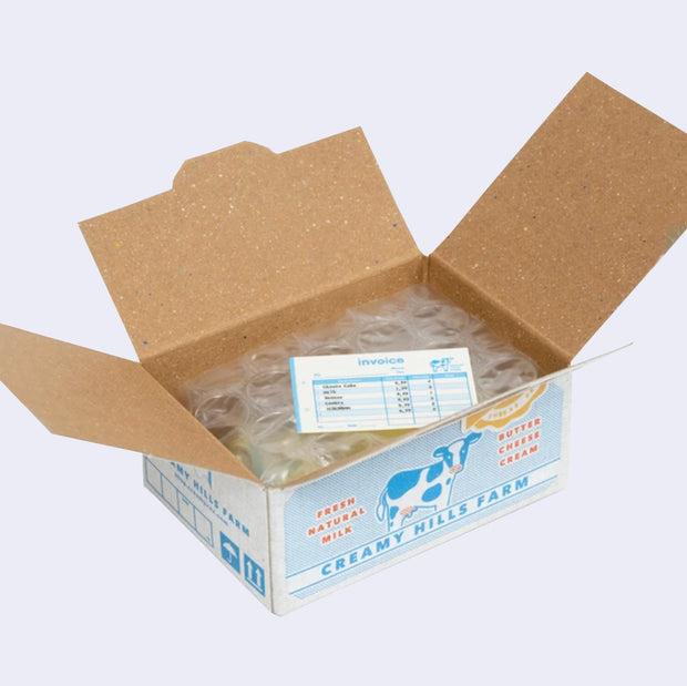 Open box of miniature stickers, made to resemble a shipping box with bubble wrap around the product and a small invoice. Exterior of box looks like realistic dairy supply box.