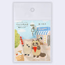 Keychain with cartoon raccoons on a scenic background, displayed on a white card.