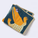 Navy blue square shaped handkerchief with a graphic of an orange illustrated crocodile with green scales, and a small purple butterfly atop its snout. Next to it re lily pads and an orange flower. Folded.