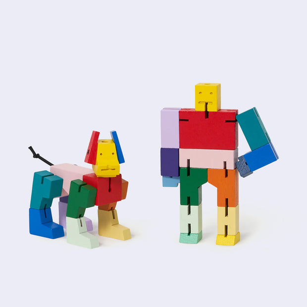 Pair of 2 wooden dolls made up of many small geometric shapes which can be reassembled into different poses. They are multicolor and one is shaped like a robot, the other like a dog.