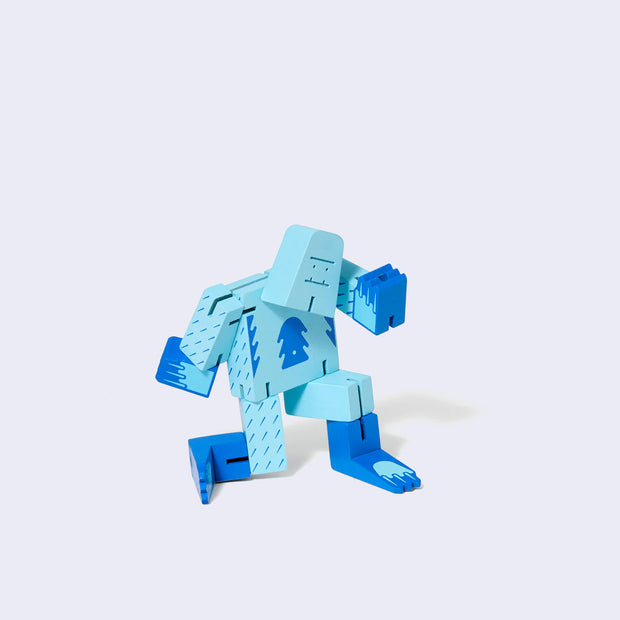 Wooden yeti character made of light and dark blue square-like shapes, standing in a dynamic pose.
