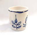 White ceramic cup with blue floral patterns on a white background
