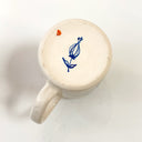 White ceramic mug with blue and red floral design on a white background