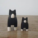 2 small wooden figurines of black and white shiba inu dogs, one is slightly smaller than the other.