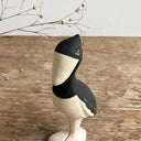 Wooden bird figurine on a wooden surface with decorative branches.