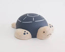 Wooden figure of a gray and white turtle with a rounded shell, flat belly and cute cartoon frown.