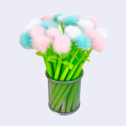 Metal cup filled with several green bodied pens with fluffy dandelion like tops. Dandelions are either pink, blue or white.