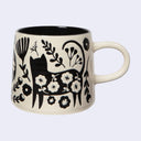 Cream colored mug with an imprinted black illustration of a cat and botanicals.