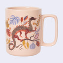 Light pink mug with an illustration of a dragon on a branch with botanicals.