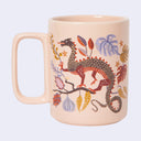 Light pink mug with an illustration of a dragon standing on a branch with botanicals around it.