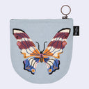A light blue zippered pouch featuring a large, colorful embroidered butterfly design in shades of purple, orange, blue, and cream. The pouch has a metal key ring attachment at the top and a small black fabric tag on the right side with the letters 'ds'.