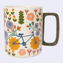 A ceramic mug with a cream-colored body decorated with a retro floral pattern and a blue bicycle motif, featuring a dark olive green handle.