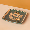 Decorative trinket dish with jewelry on a beige surface and orange background