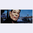 Large mask of a smiling man with a city street scene in the background