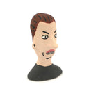 A hand-painted clay figurine of a man's head with brown hair, a beige face, black outlines, and a black shirt, shown against a plain white background.