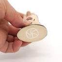 A hand holding a small ceramic figurine head, showing the underside of the base with a white geometric logo on a plain white background.