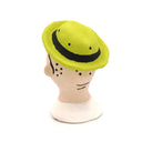 A handcrafted clay figurine of a man's head wearing a bright lime green hat and black-rimmed glasses with white circular lenses, set against a plain white background.
