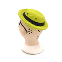 A handcrafted clay figurine of a man's head wearing a bright lime green hat and black-rimmed glasses with white circular lenses, set against a plain white background.