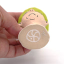 A handcrafted clay figurine of a man's head wearing a bright lime green hat and black-rimmed glasses with white circular lenses, set against a plain white background.