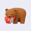 Brown bear figurine holding a red fish-shaped object with a label on a light gray background
