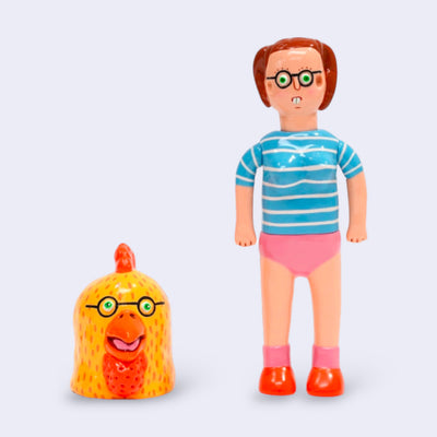 Vinyl figure of a woman with glasses, short hair and buck teeth. She wears a blue striped top and pink underwear. Next to her is a large chicken head, also with glasses.