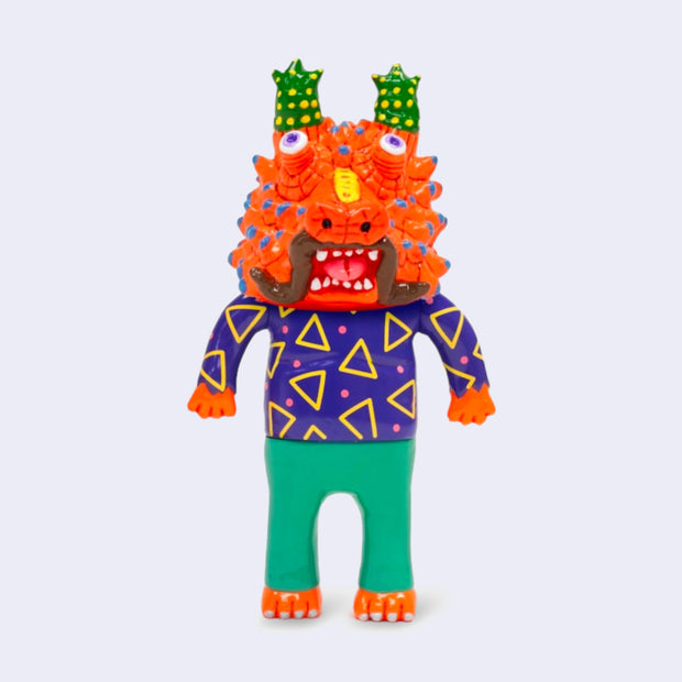 Vinyl figure of a man wearing a bright purple shirt with triangles and green pants. Atop his head is a bright orange dragon head, with many horns atop its head and on its face.