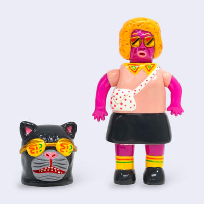 Vinyl figure of a pink woman with a blonde short perm and glasses. She wears a crossbody bag and a skirt. Near her is a large black cat head with similar looking sunglasses.