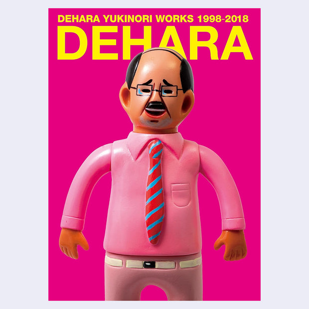 Book cover for Dehara "Works 1998-2018", fluorescent pink with a vinyl figure of a balding Japanese business man on the cover, wearing a pink shirt and pink striped tie.