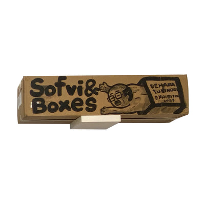 Painted cardboard box that says "Sofvi & Boxes" with an illustration of a nude business man coming out of a box.