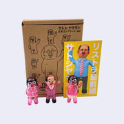 Set of 3 small vinyl figures of little business men. One wears a pink suit and waves. Another has black hair, pink skin and wears a tan briefs. The final figure has black hair, pink skin and wears pink bondage type attire.