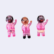 Set of 3 small vinyl figures of little business men. One wears a pink suit and waves. Another has black hair, pink skin and wears a tan briefs. The final figure has black hair, pink skin and wears pink bondage type attire.