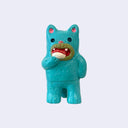 Vinyl figure of a small teal blue cat standing on 2 legs like a person and holding a piece of sushi, putting it in its mouth.
