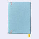 Backside of bluish gray pleather covered journal with an elastic closure and a shiny yellow page marking ribbon.