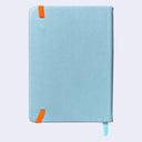 A light blue hardcover notebook with bright orange elastic closure tabs and a matching light blue ribbon bookmark, shown on a plain light gray background.