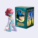 Colorful figurine with pink hair and blue outfit next to its packaging on a light purple background