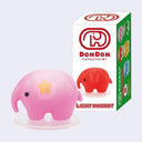 A pink elephant-shaped light up figurine with a small yellow flower on its ear, displayed in front of its white and green DomDom product box on a light gray background.