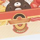 Cartoon bear character peeking out from a donut box with a donut design on the box.