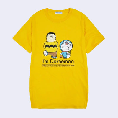 Yellow t-shirt featuring a graphic of Doraemon and a human wearing a Charlie Brown esque shirt. They both walk and kick up one foot. Below, reads "I'm Doraemon!"