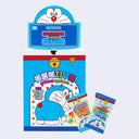 A box of Doraemon-themed random choice erasers with two individual eraser packets placed in front on a light gray background.