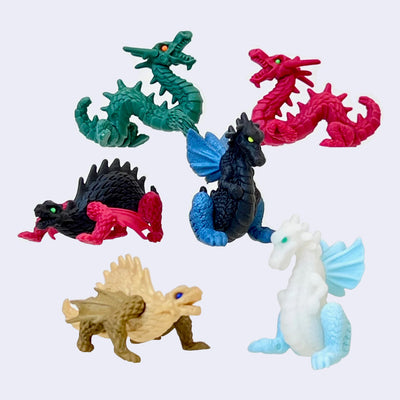 Set of colorful dragon erasers on a light gray background